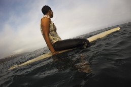 African American woman on a surfboard, waiting for a wave at Malibu