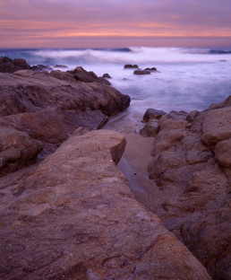 Sunrise over rocky shore with distant waves