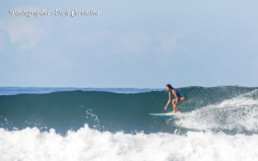 Costa RIcan woman surfs an open green wave.